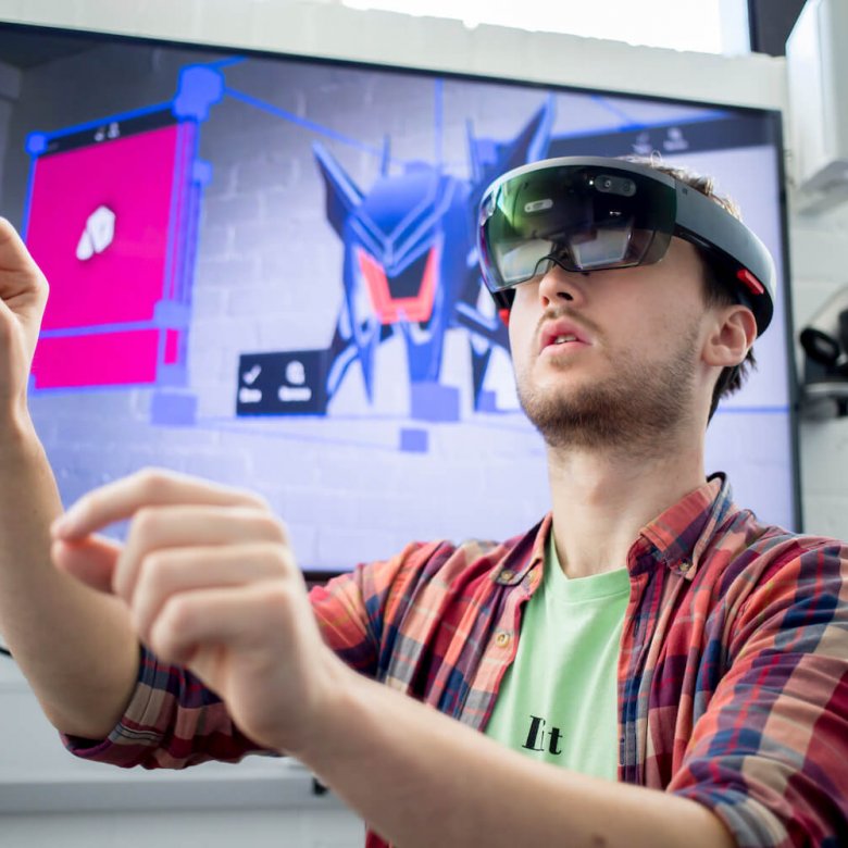 A Falmouth University student wearing a VR headset and a checked shirt