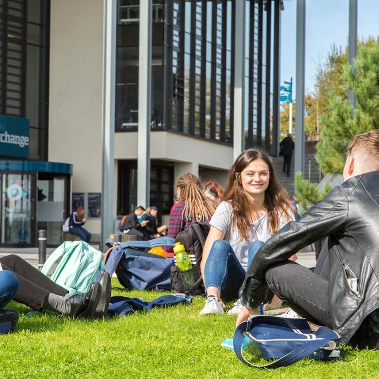 Penryn campus students outside exchange, sitting on grass