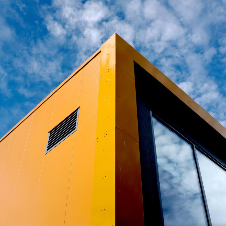 Orange and black Penryn Campus Sports Hall building with blue sky in the background