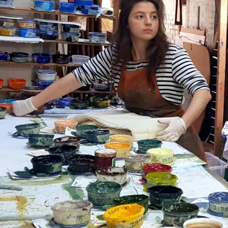 A girl in a studio surrounded by paint pots