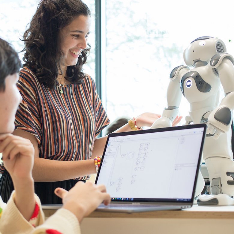 Two Robotics students operating a small robot with a laptop