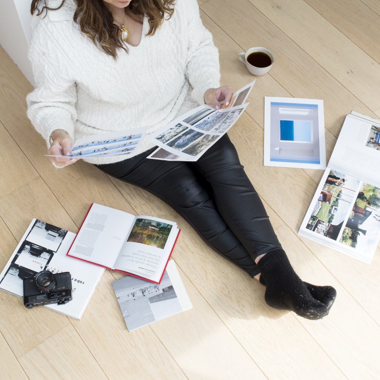 An online photography student sat on the floor with their work