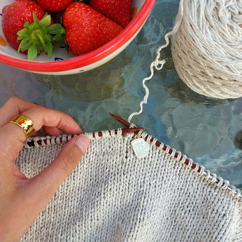 A bird's eye shot of some knitting and a bowl of strawberries