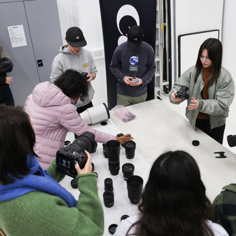 A group of students stood around a white table looking at camera equipment