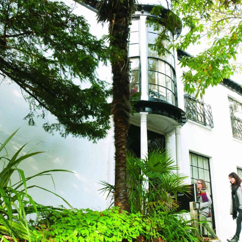 A white building behind greenery