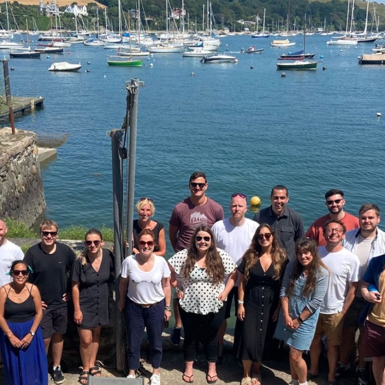 A large group of people standing in front of the sea and boats