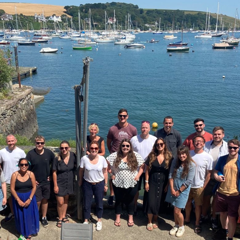 A large group of people standing in front of the sea and boats