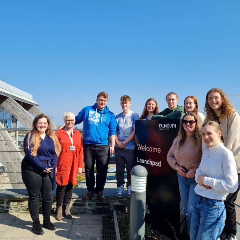 A group of Business & marketing students huddled together under blue sky during their micro-internship with Launchpad Venture Studio