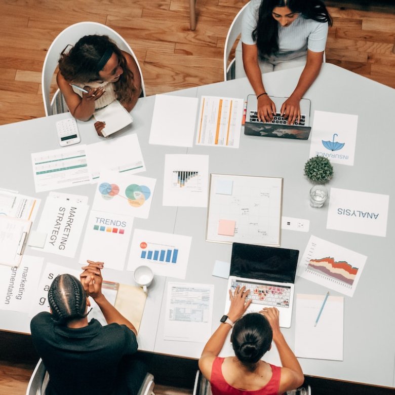 Birds eye view of group of people sat around a table with business strategy papers