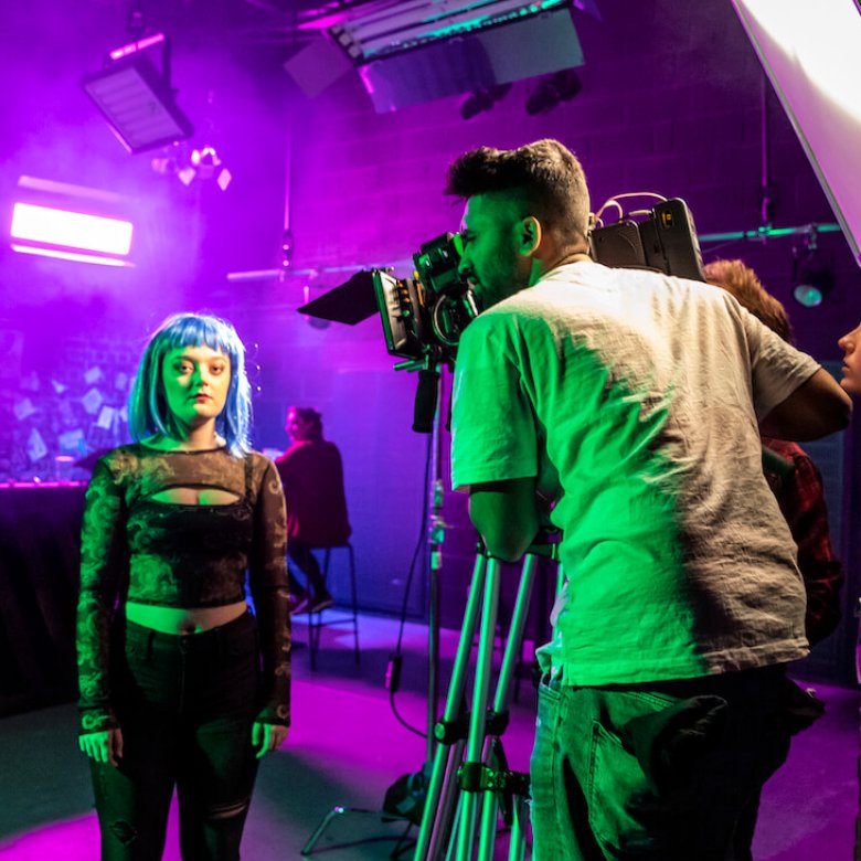 Falmouth University students in a purple lit film studio with camera