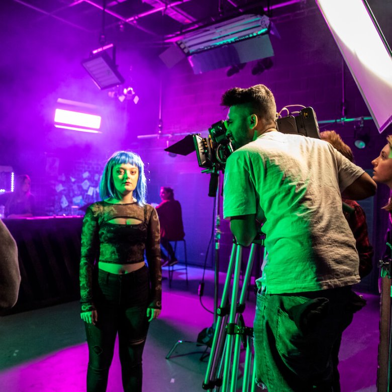 Falmouth University students in a purple lit film studio with camera