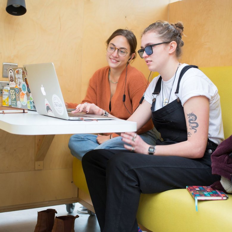 Two students working together around a laptop