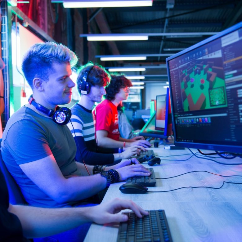 Games academy students sit side-by-side looking at computer screens