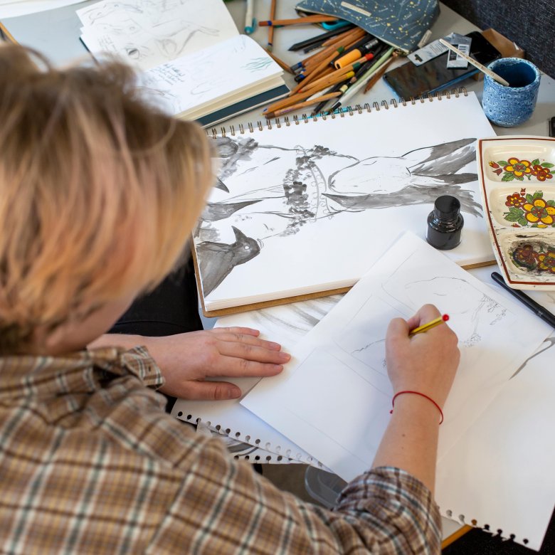 Falmouth Illustration student at cluttered desk drawing a rabbit