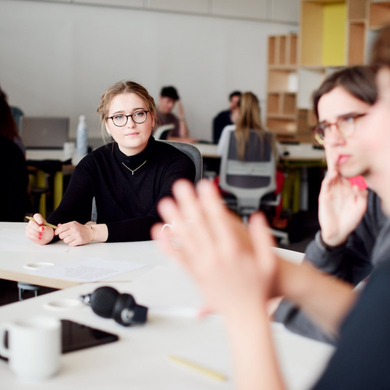 Three people around a white office table