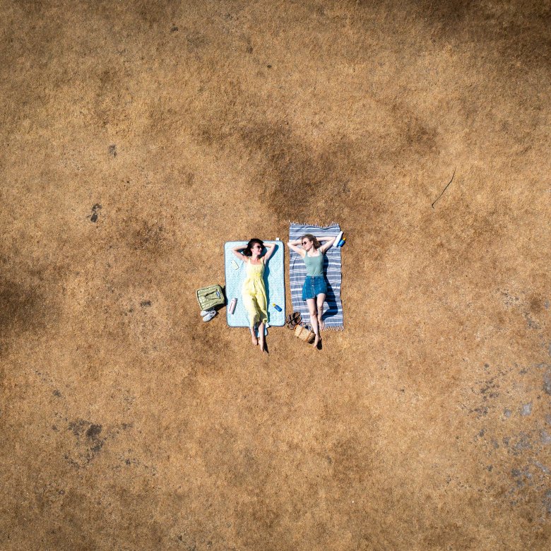Two sunbathers lying on scorched grass