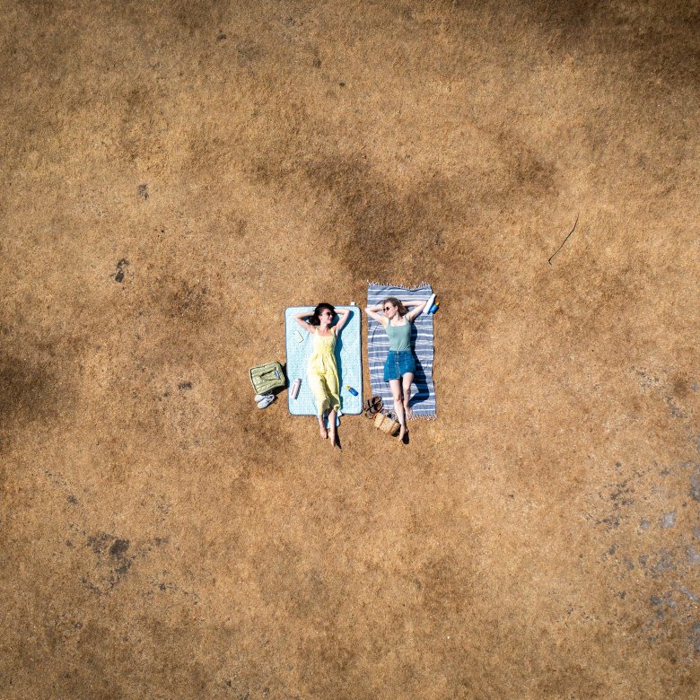 Two sunbathers lying on scorched grass 