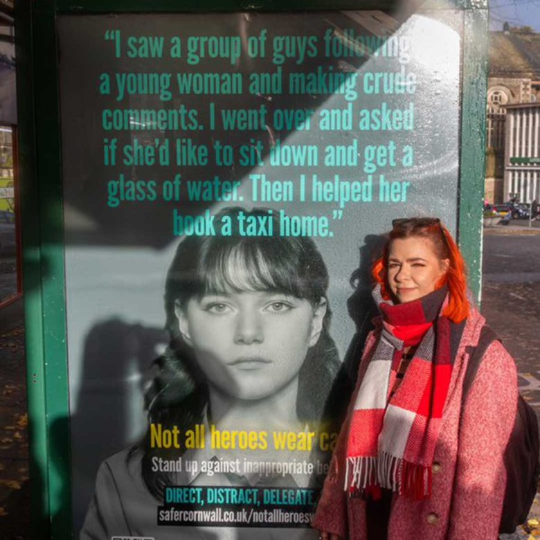 Student Justyna Skowronska standing next to her Safer Cornwall campaign bus stop advert