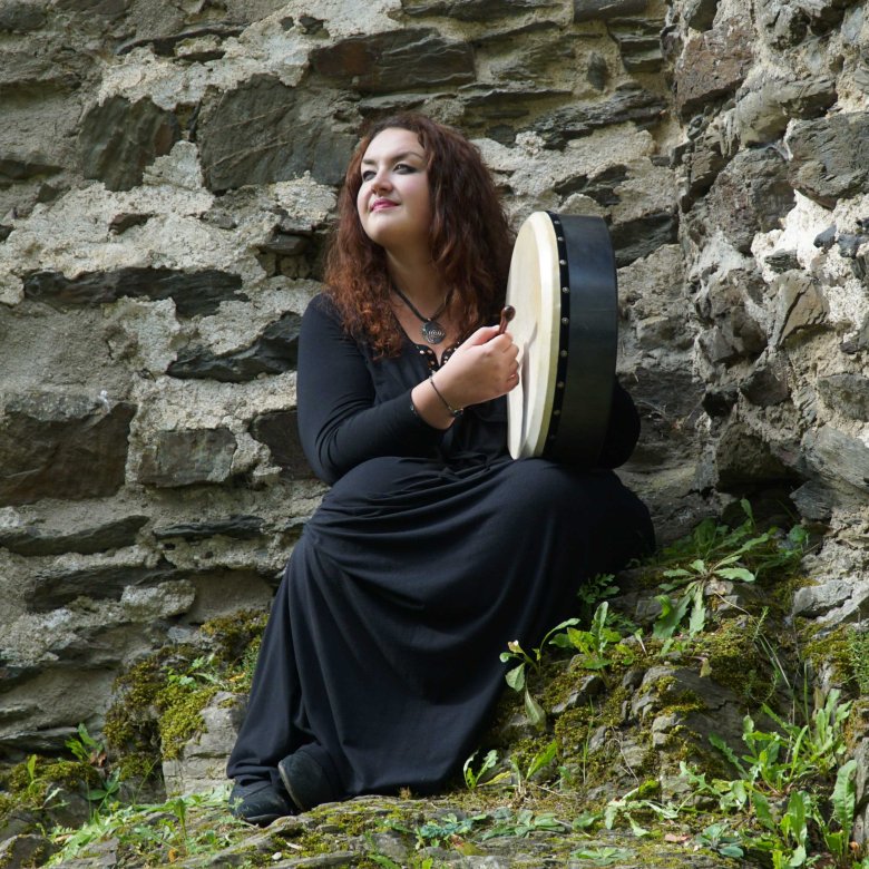 Helen Leahey playing a tambourine on a mountainside 