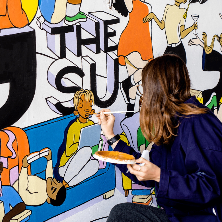 Student painting Students' Union mrual on Penryn Campus