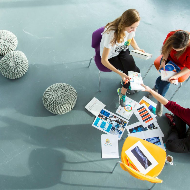 Three Falmouth Business students looking at graphs