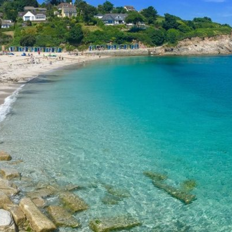 View of Swanpool Beach with turquoise water and beach huts