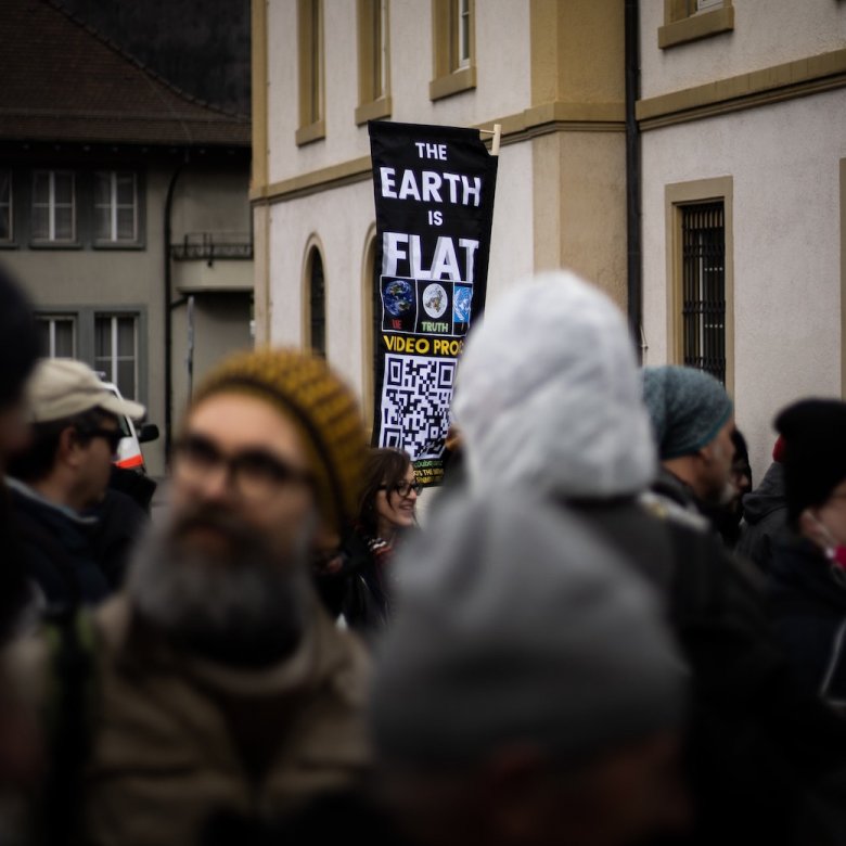 A banner raised above a crown with the text 'the earth is flat'