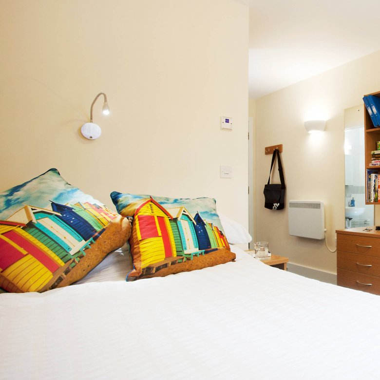 An empty university room, equipped with double bed and desk