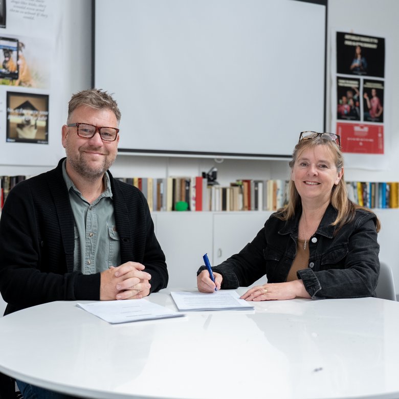 Two people signing an agreement