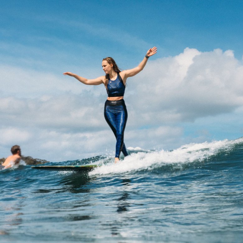 Photo of Falmouth graduate Abbi Hughes surfing on longboard in Cornwall