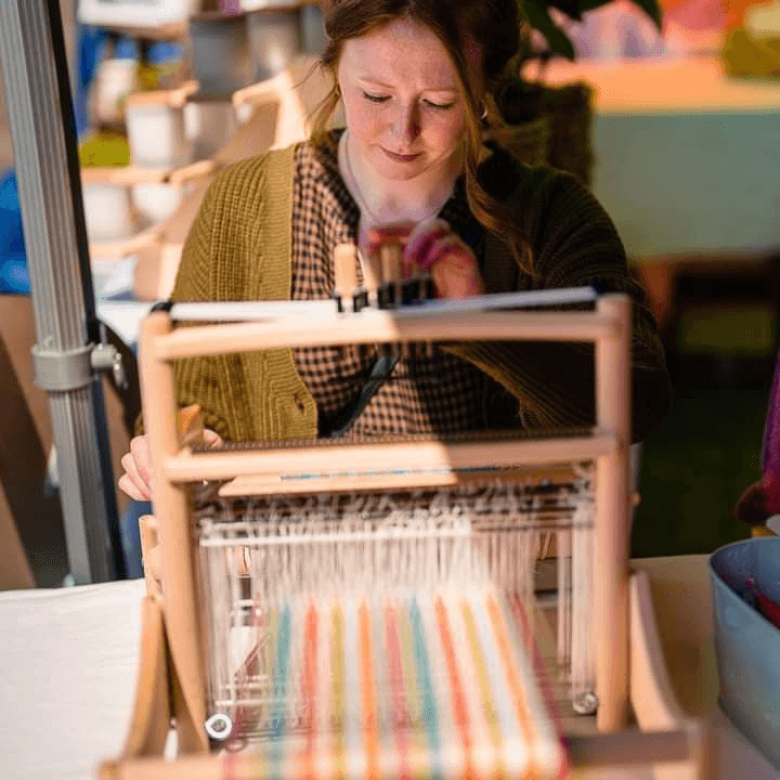 A woman sat in front of a loom