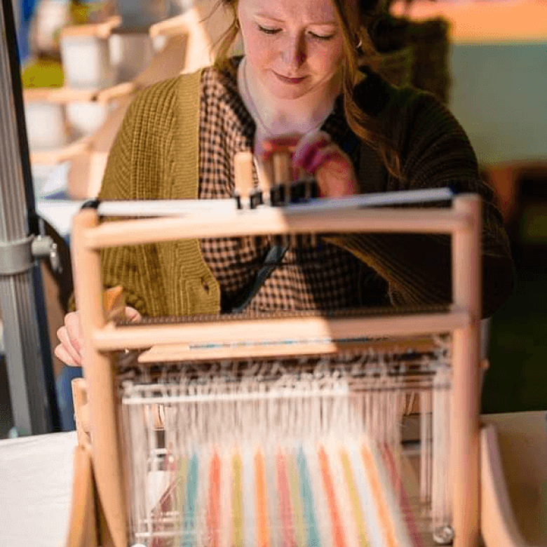 A woman sat in front of a loom