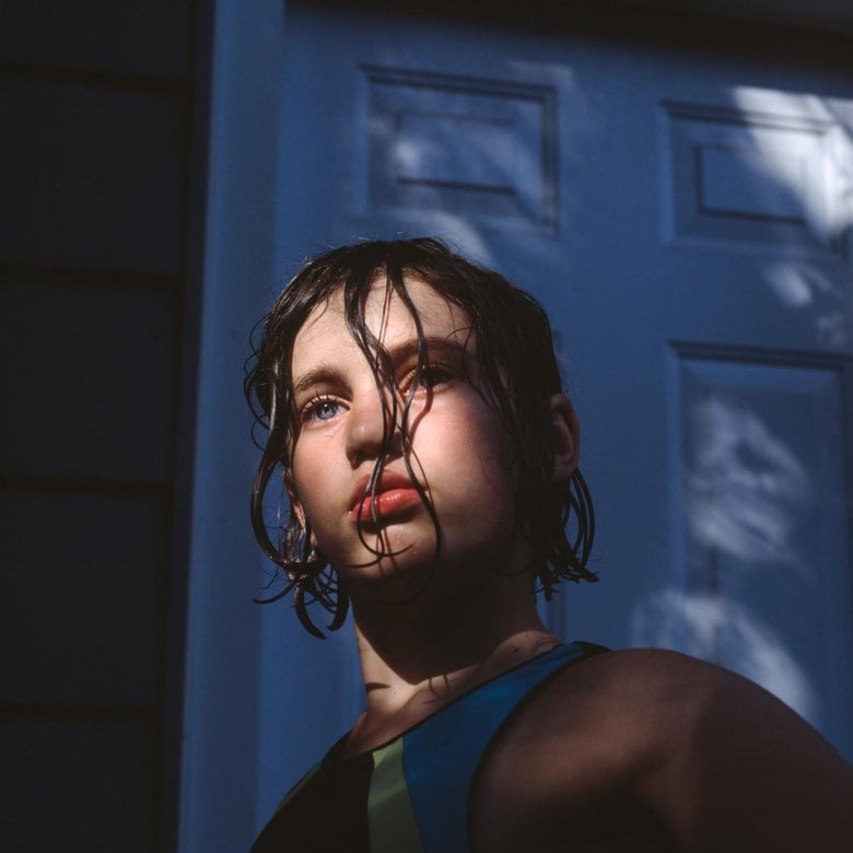 Photograph of a girl with dark wet hair with the sun on her face