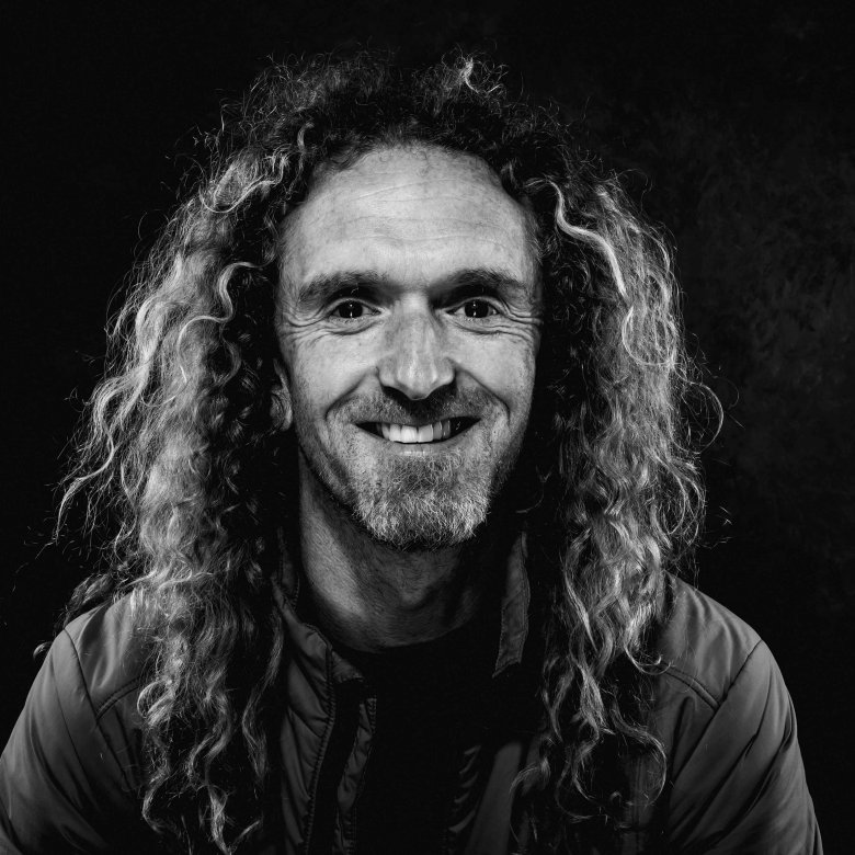 Black and white photo of a man with curly long hair