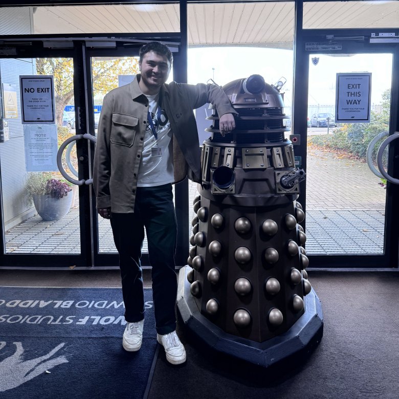 Television graduate Charles Jackson standing with Dalek in Doctor Who studios