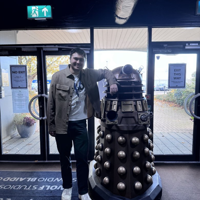 Television graduate Charles Jackson standing with Dalek in Doctor Who studios