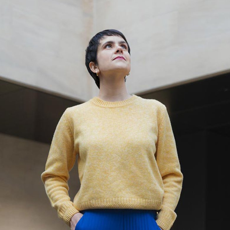 A woman wearing a yellow jumper and blue trousers