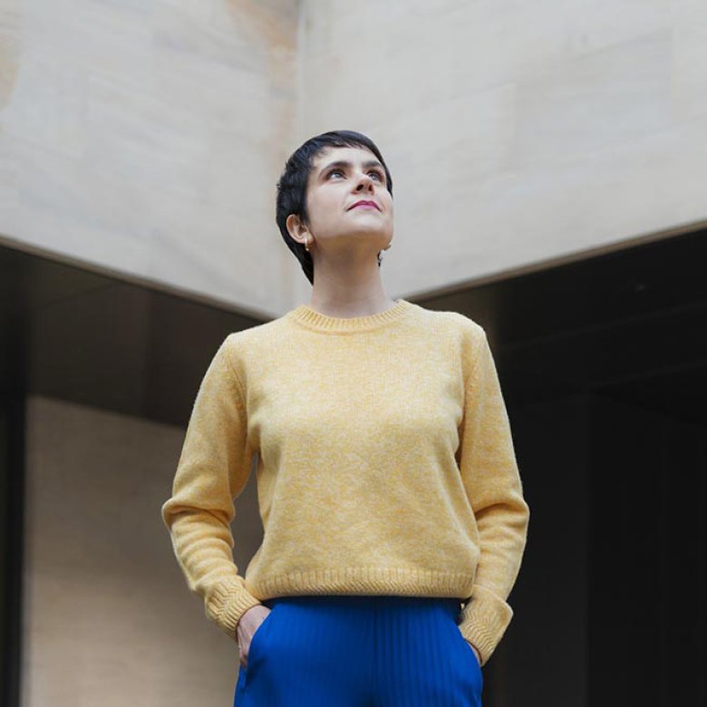 A woman wearing a yellow jumper and blue trousers