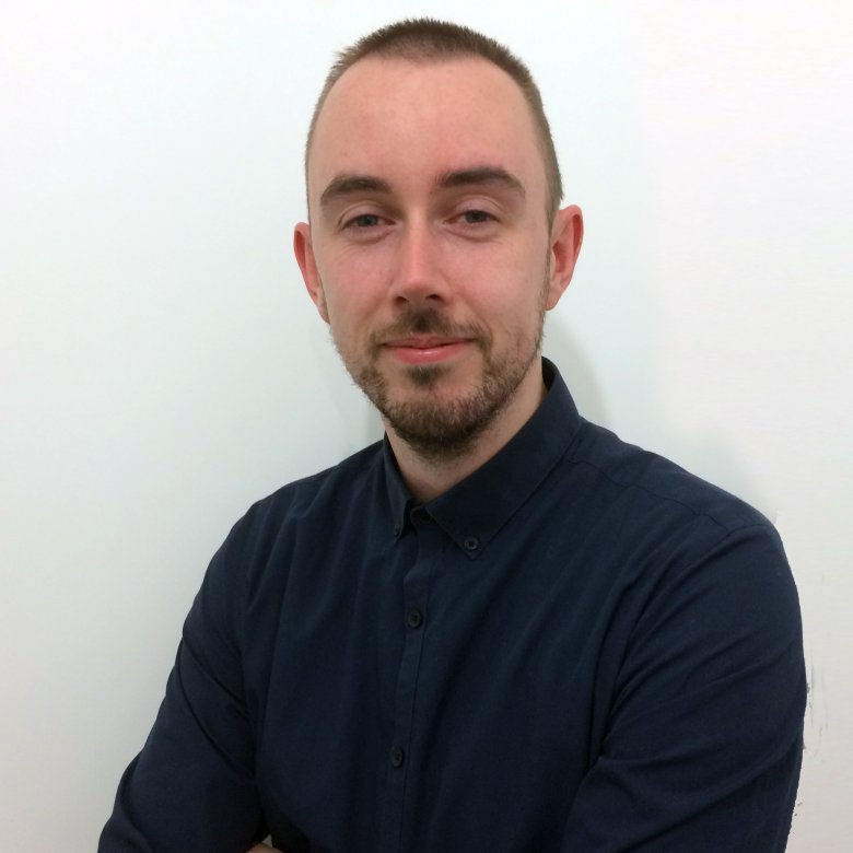 A headshot of Dr John Finnegan sat against a white wall