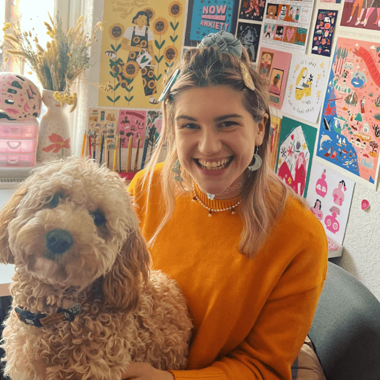 A young woman wearing an orange jumper with a dog on her lap