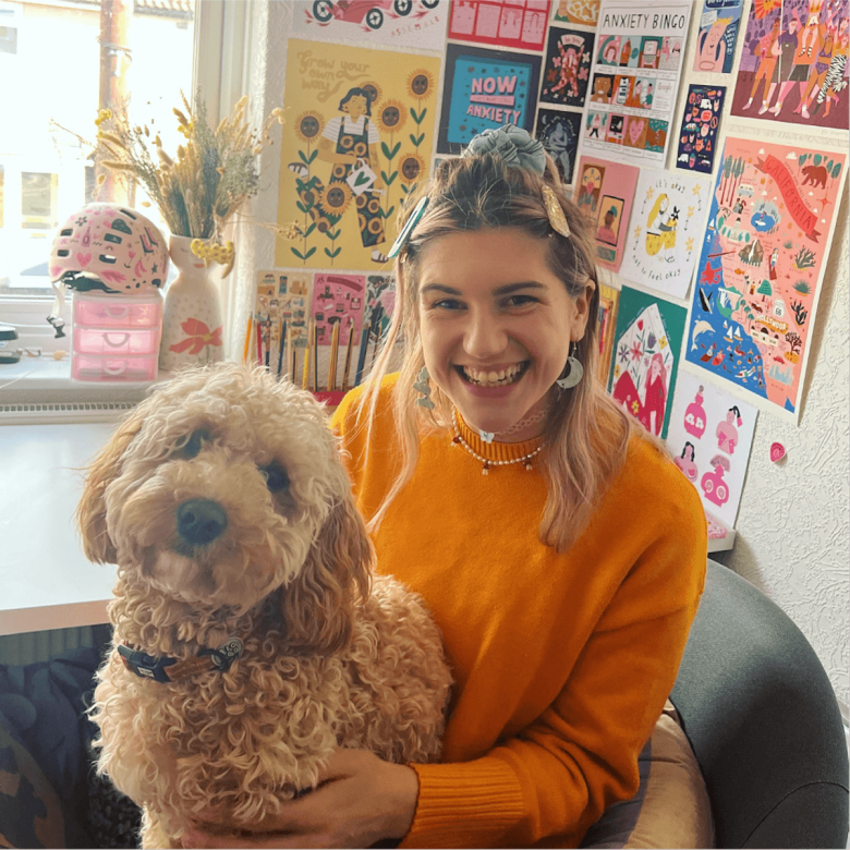 A young woman wearing an orange jumper with a dog on her lap
