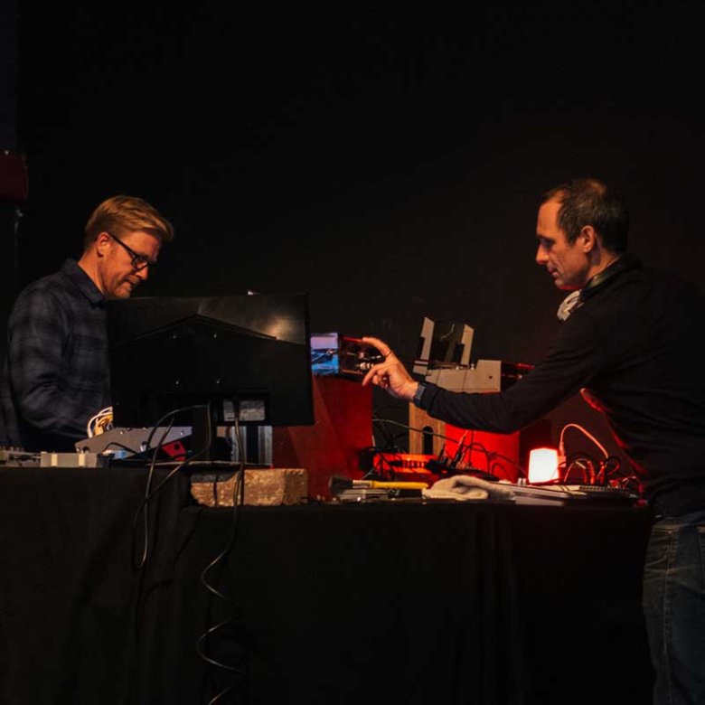 Two men on a stage using analogue equipment to perform a live film score