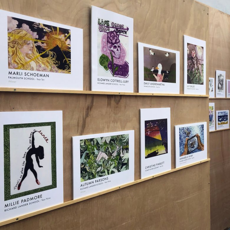 Two rows of printed postcards displayed on a wooden board