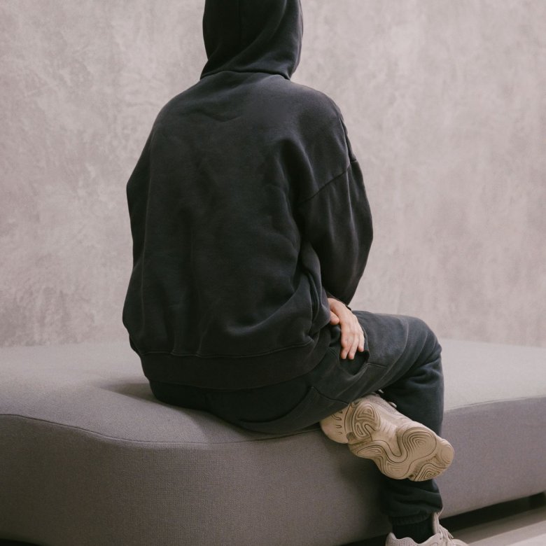 Photo of Fashion Design graduate Finlay Vincent facing away from the camera wearing black hoody with the hood up.