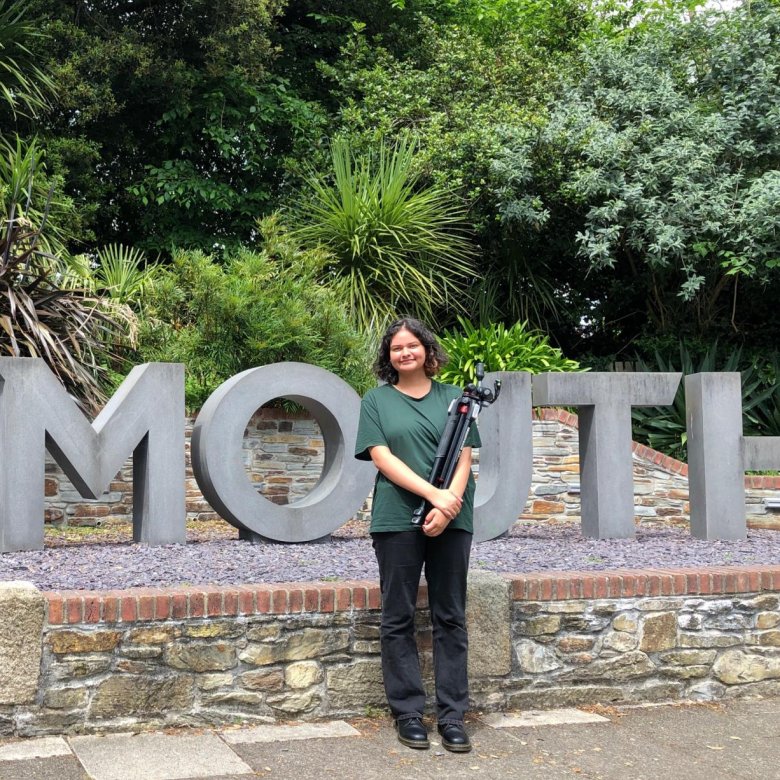 A woman stands in front of the Falmouth sign on Woodlane