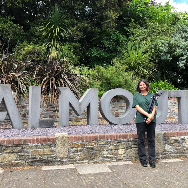 A woman stands in front of the Falmouth sign on Woodlane