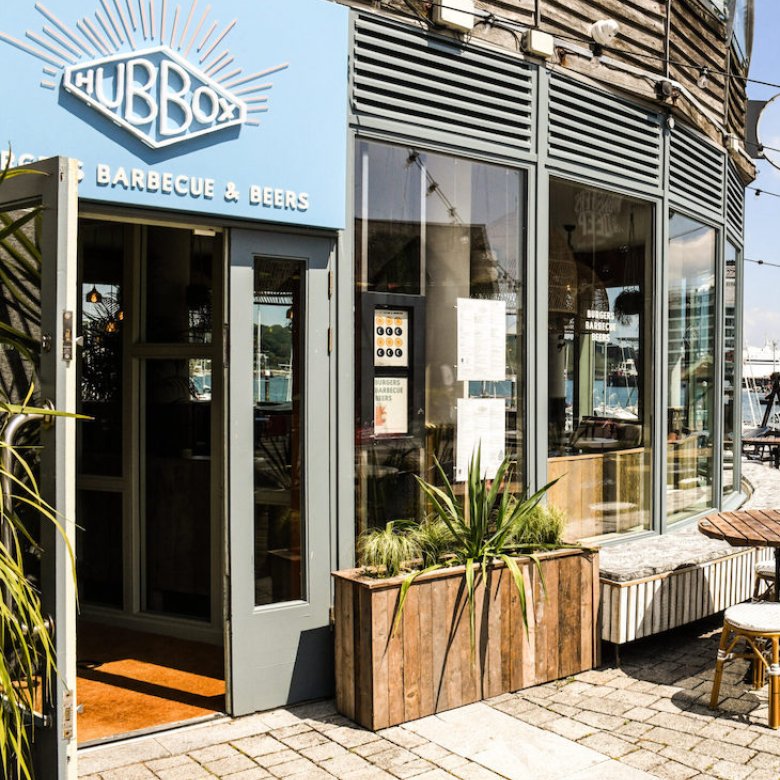 Hub Box restaurant exterior building with planters, tables and chairs