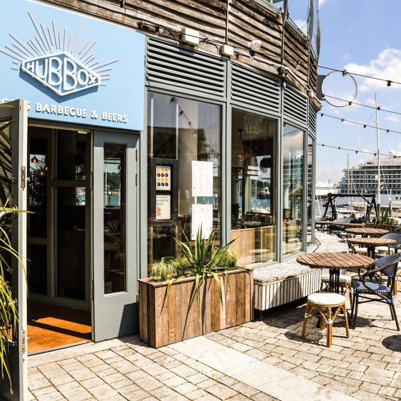 Hub Box restaurant exterior building with planters, tables and chairs