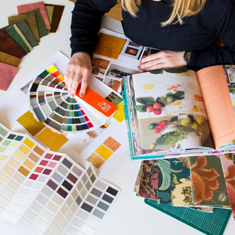 A student on interior design sitting at a table with books, paint and fabric samples in front of them