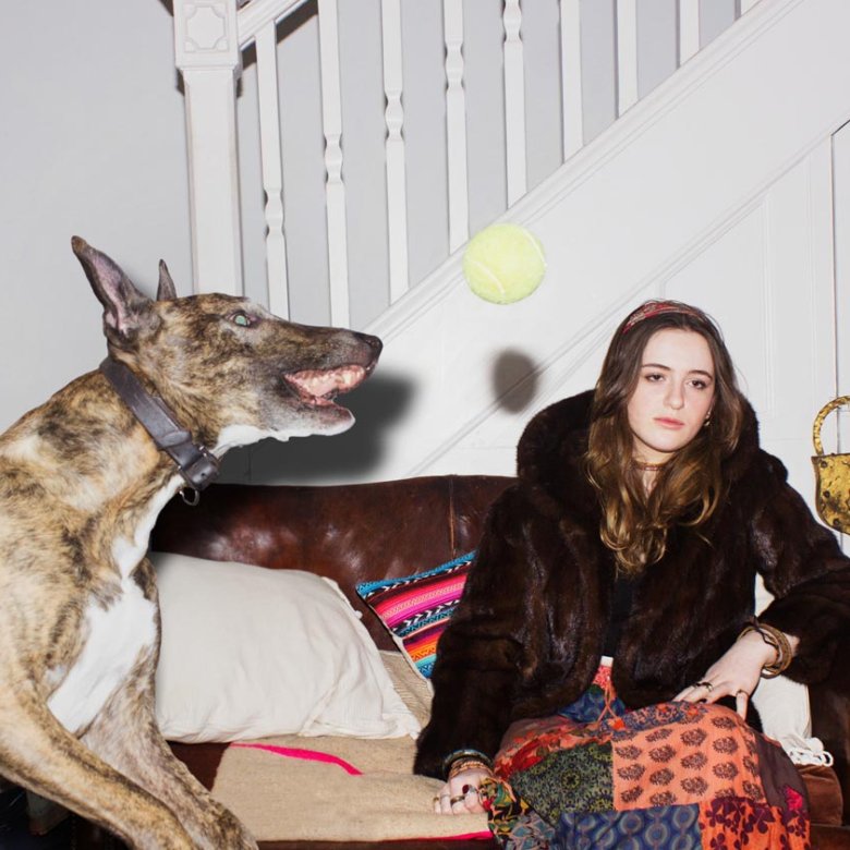 A young woman sitting on a sofa with a large dog jumping up